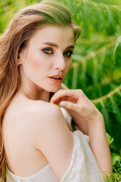 Retrato de una hermosa mujer en un vestido blanco contra el de hojas verdes. —  Fotos de Stock