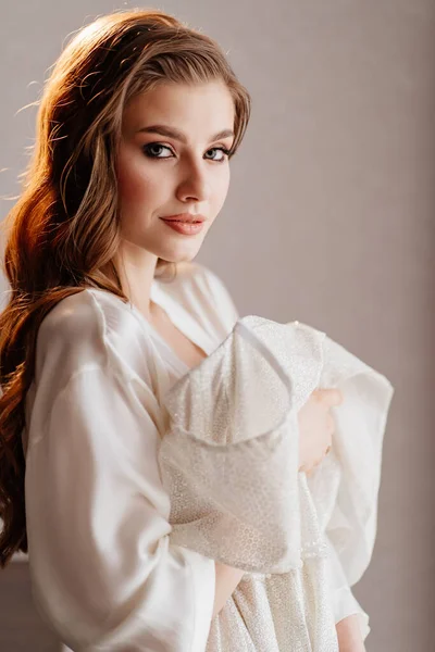Portret van mooie vrouw in witte mantel houden trouwjurk in de voorkant van haar — Stockfoto