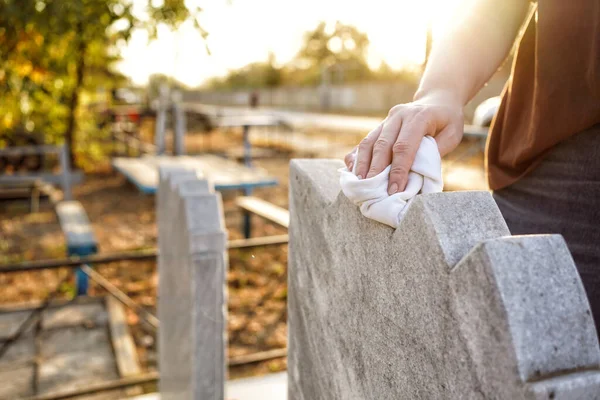 Friedhofsreinigung. Eine Frauenhand wäscht graues Denkmal am Grab mit Lappen. — Stockfoto