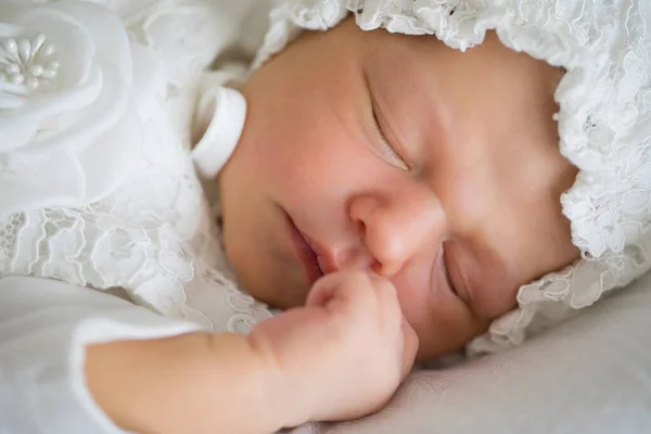 Un bebé recién nacido con ropa blanca y un sombrero está durmiendo. —  Fotos de Stock