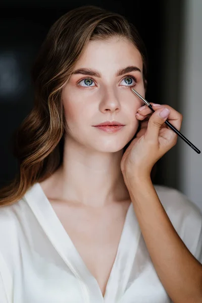 Seorang wanita muda cantik dengan rambut panjang melakukan makeup untuk pernikahan atau pemotretan — Stok Foto