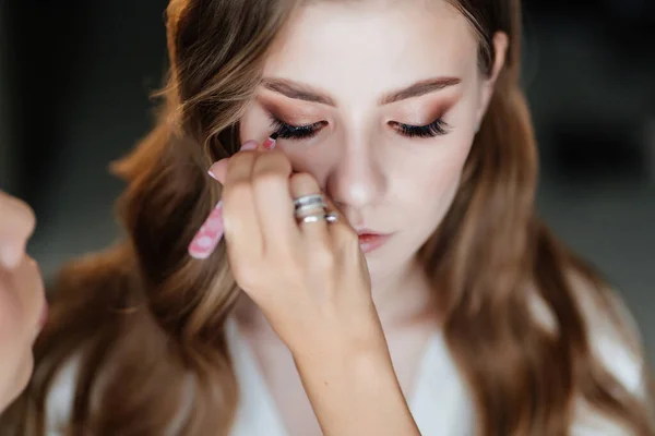 Krásná mladá žena s dlouhými vlasy dělat make-up pro svatbu nebo focení — Stock fotografie