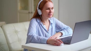 Kulaklıklı kadın evde dizüstü bilgisayarla çalışıyor. Ders veriyor ya da web sitesi kuruyor..