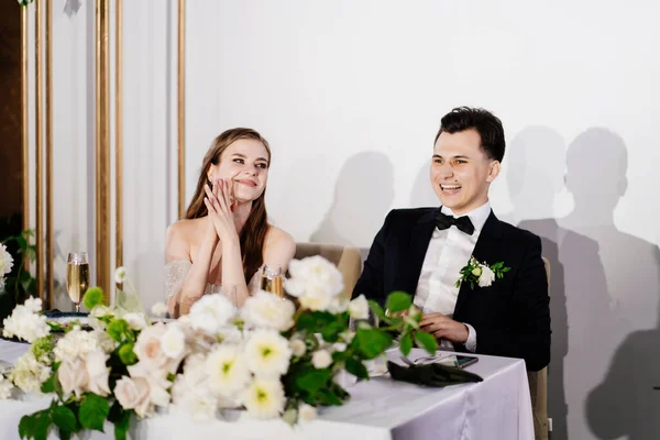 คู่สมรสใหม่ฟังขนมปังปิ้งแสดงความยินดีจากแขกและหัวเราะ — ภาพถ่ายสต็อก