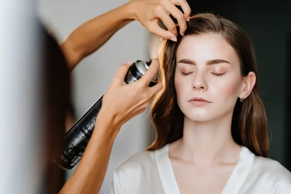 Una bella donna con i capelli lunghi fare hair styling per un matrimonio o servizio fotografico — Foto Stock