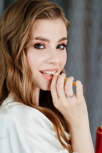 Mooie jonge vrouw met lang haar en make-up eten van frietjes. — Stockfoto