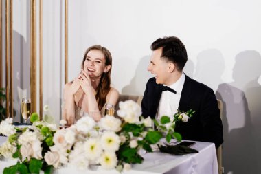 Yeni evliler kadeh kaldırır, konukları tebrik eder ve gülerler.