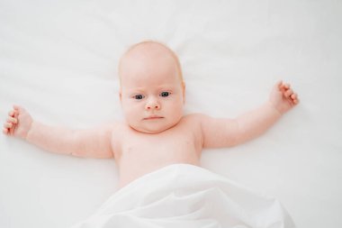 Sevimli kızıl saçlı bebek beyaz bir yatakta yatıyor. Bebek bakımı kavramı