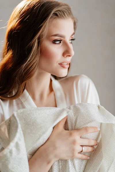 Retrato de mujer hermosa en túnica blanca sosteniendo vestido de novia delante de ella — Foto de Stock