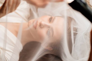 Üstü görünüyor. Güzel genç bir kadın peçenin altında yatıyor. Ellerini yüzüne koy..