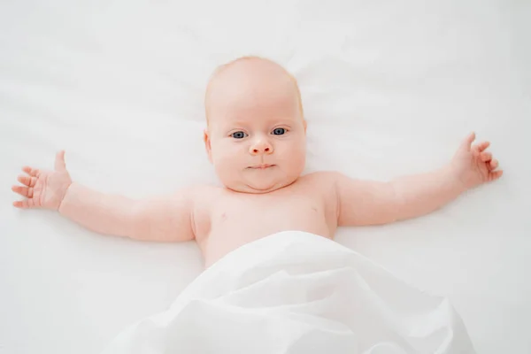Bebê ruivo bonito encontra-se em uma cama branca. conceito de cuidado do bebê — Fotografia de Stock