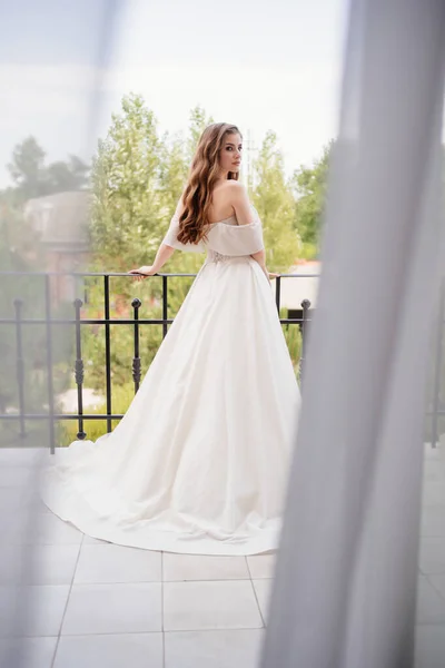 Rear view. beautiful young woman in a white wedding dress stands on terrace. — Stock Photo, Image