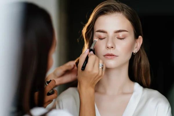 Krásná mladá žena s dlouhými vlasy dělat make-up pro svatbu nebo focení — Stock fotografie