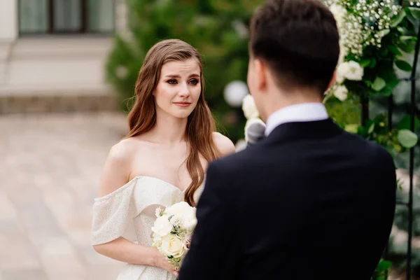 Hochzeitszeremonie im Bogen der Blumen. Braut hört auf das Gelübde und die Schreie der Bräutigame. — Stockfoto