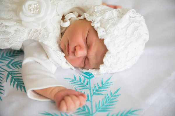 Ett nyfött barn i vita kläder och en hatt sover. — Stockfoto