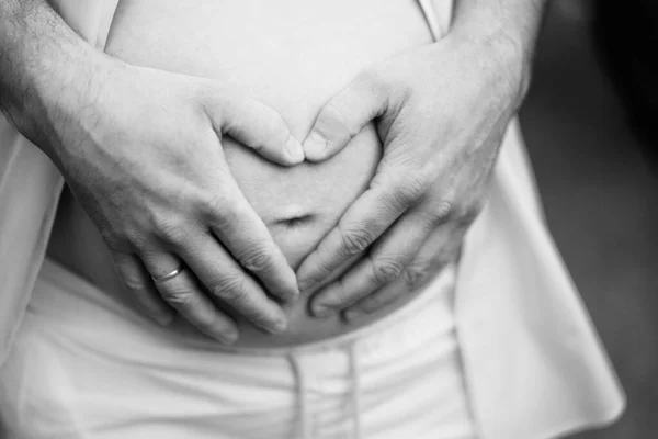 Preto-branco. homens mãos na barriga de uma mulher grávida. — Fotografia de Stock