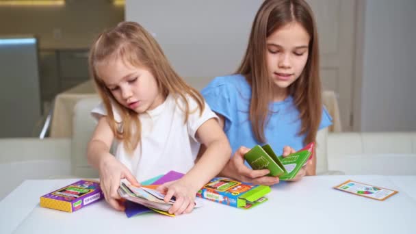 Κορίτσια ξεπακετάρετε με νέες κάρτες ανάπτυξης και κατάρτισης. επιτραπέζια παιχνίδια για παιδιά. — Αρχείο Βίντεο