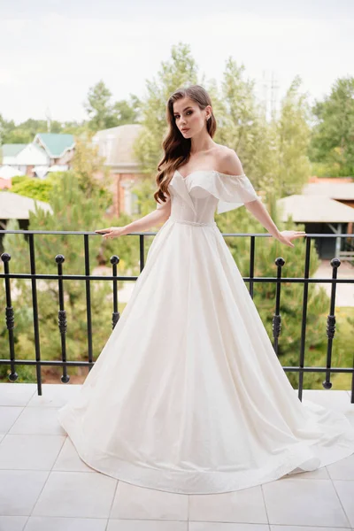하얀 웨딩 드레스를 입은 아름다운 한 젊은 여자가 테라스 위에 서 있다. — 스톡 사진
