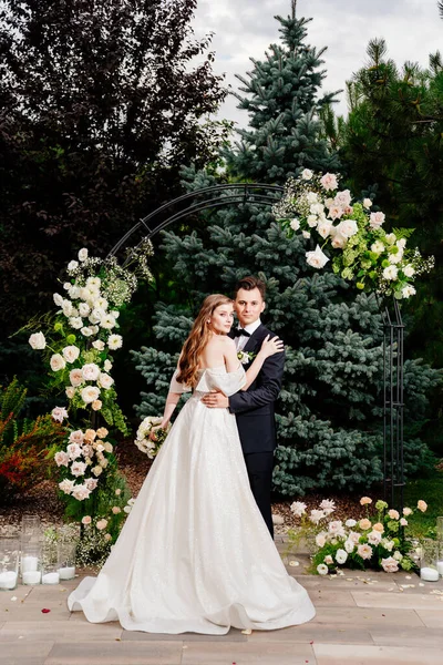 Buiten huwelijksceremonie in een boog van levende bloemen.Mooi paar pasgetrouwden — Stockfoto