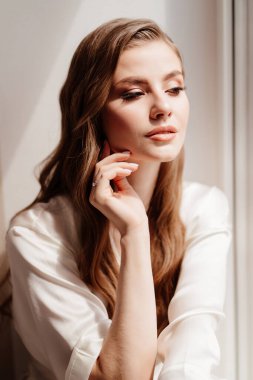 Pencerede beyaz cüppeli güzel bir kadın. Düğünden önce gelinin sabahı.