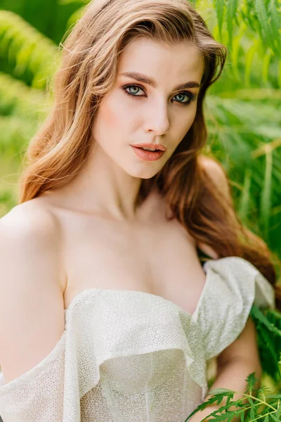 Retrato de uma bela mulher em um vestido branco contra o de folhas verdes. — Fotografia de Stock
