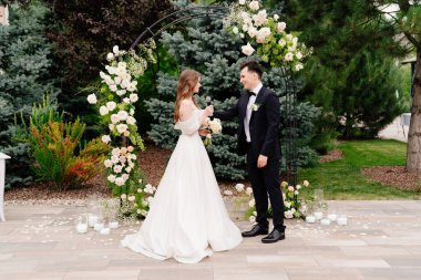 Canlı çiçeklerin kemerinde bir düğün töreni. Gelin der düğün yemini eder ve ağlar