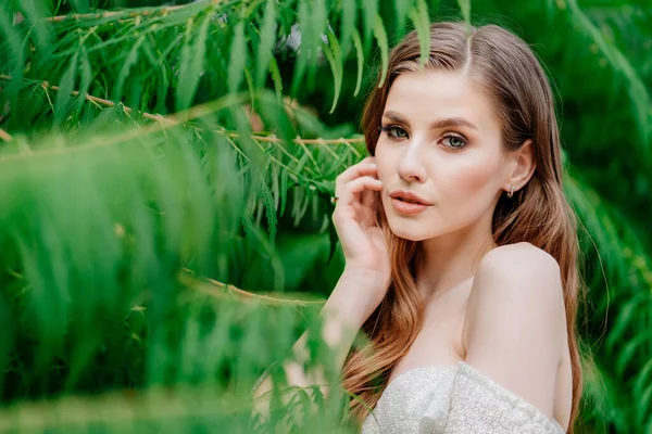 Retrato. hermosa mujer con ojos claros en vestido blanco contra de hojas verdes — Foto de Stock