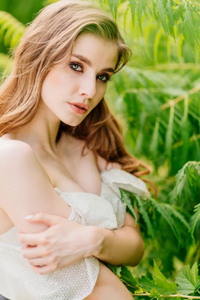 Retrato de uma bela mulher em um vestido branco contra o de folhas verdes. — Fotografia de Stock