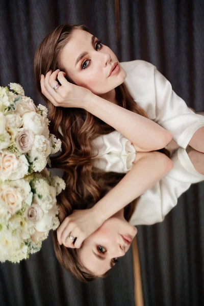 흰옷을 입고 꽃다발이 놓여 있고 거울에 비친 아름다운 여인. — 스톡 사진