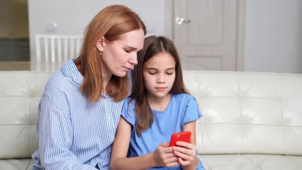 Mamá enseña a su hija a usar un teléfono inteligente, ver fotos, videos a través de Internet — Vídeos de Stock