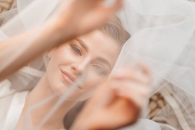 Üstü görünüyor. Güzel genç bir kadın peçenin altında yatıyor. Ellerini yüzüne koy..