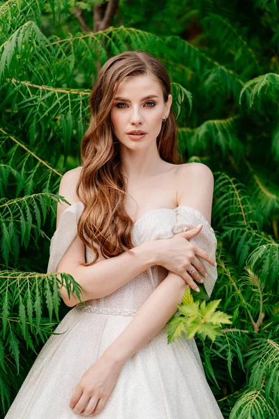 하얀 드레스를 입은 아름다운 여인이 푸른 잎을 마주 보며 포즈를 취하는 모습. — 스톡 사진