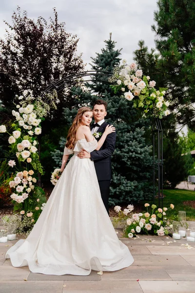 Cérémonie de mariage en plein air dans une arche de fleurs vivantes.Beau couple jeunes mariés — Photo
