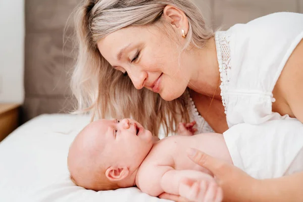 Mamá es mamá está acostada con un bebé en una cama blanca después de alimentar a la leche materna. —  Fotos de Stock