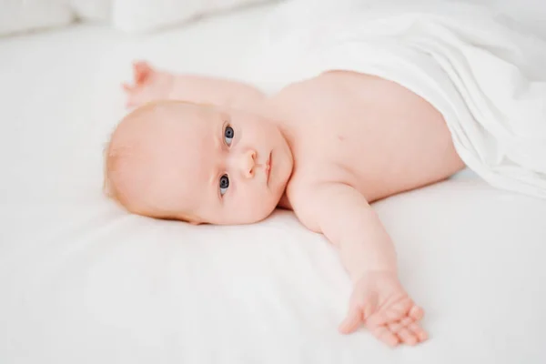 Bebê ruivo bonito encontra-se em uma cama branca. conceito de cuidado do bebê — Fotografia de Stock