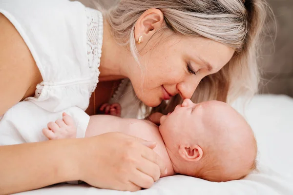 Mamá es mamá está acostada con un bebé en una cama blanca después de alimentar a la leche materna. — Foto de Stock