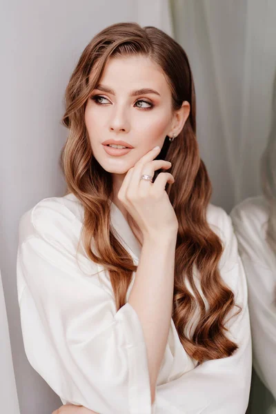 Belle femme en robe blanche à la fenêtre.matin de la mariée avant le mariage — Photo