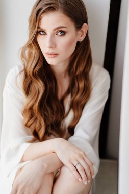 Beyaz cüppeli güzel bir kadın pencere kenarında oturur. Gelinin düğünden önceki sabahı.