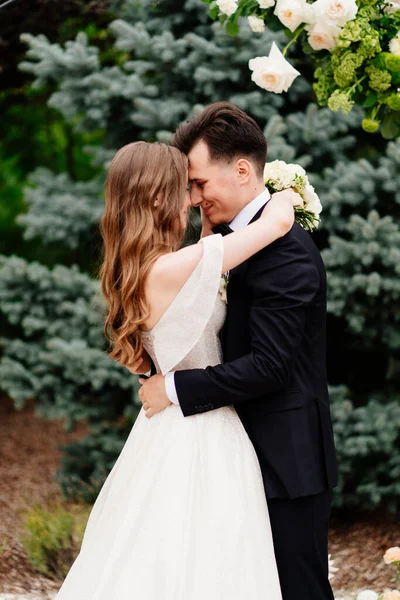 Cérémonie de mariage en arc de fleurs vivantes.Belles jeunes mariés embrassent tendrement — Photo