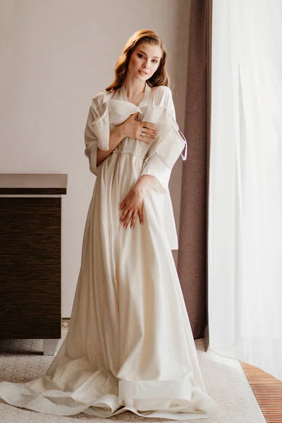 Mooie vrouw in wit gewaad houden trouwjurk in de voorkant van haar — Stockfoto