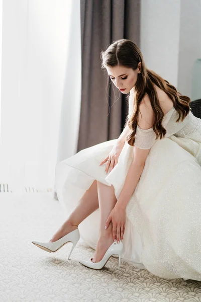 Una hermosa novia se pone zapatos. Preparación para la ceremonia de boda. — Foto de Stock