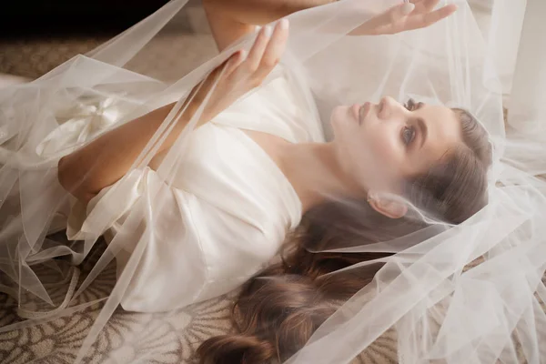 Красивая молодая женщина в халате лежит под вуалем. — стоковое фото
