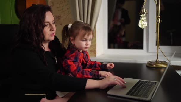 幼い娘はフリーランスの母親がコンピュータで働くのを防ぎ. — ストック動画