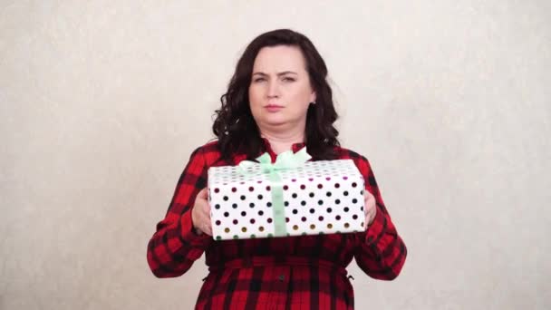 A woman in a red holds a packed gift, holds it out and then takes it back. greed — Stock Video