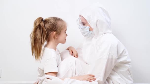 Uma menina abraça um médico em um terno branco de proteção, máscara, óculos e luvas — Vídeo de Stock