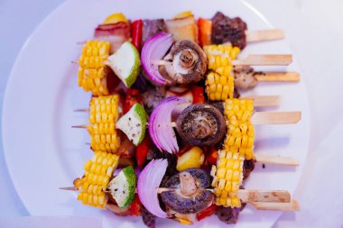 Sebzelerden, mantarlardan, mısırlardan, soğanlardan oluşan kanepeler beyaz tabakta. 