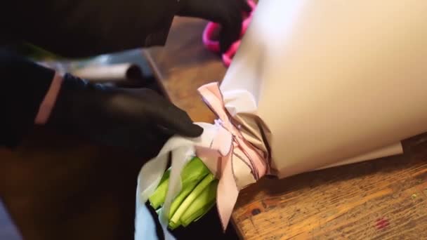 Floristen binder pilbågen på buketten och klipper bandet med sax. — Stockvideo