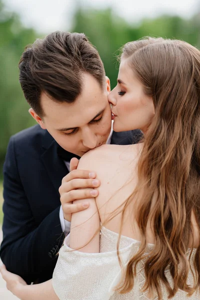 Sposa e sposo belli, gentili e felici. uomo bacia dolcemente le donne spalla — Foto Stock