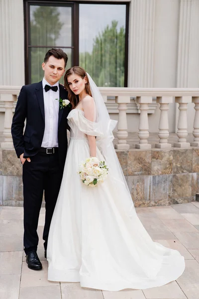 Schöne Brautpaare stehen vor dem Hintergrund eines hellen Gebäudes. — Stockfoto