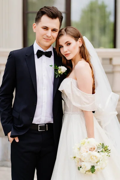 Bellissimi sposi stare sullo sfondo di un edificio leggero. — Foto Stock